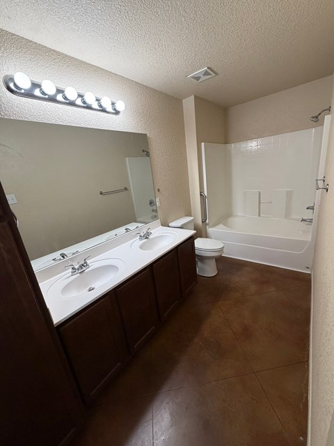A bathroom with brown floors and a white tub.