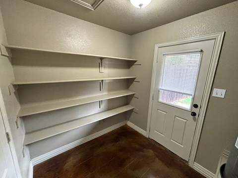 Empty room with white shelves and a door.