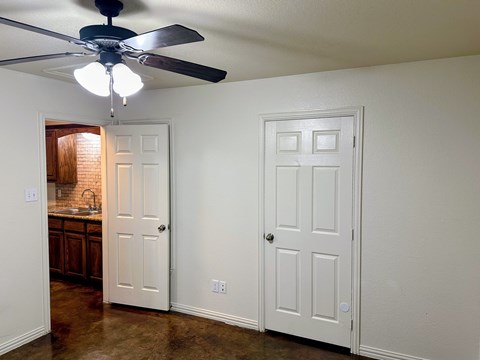 A room with a ceiling fan and two doors.