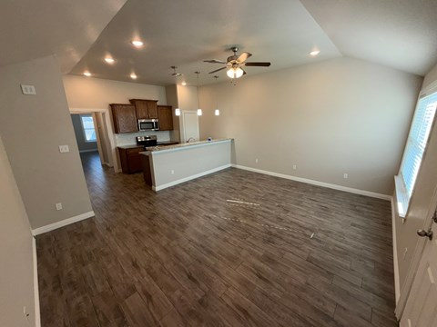 A room with a kitchen area in the background and a living room area in the foreground.