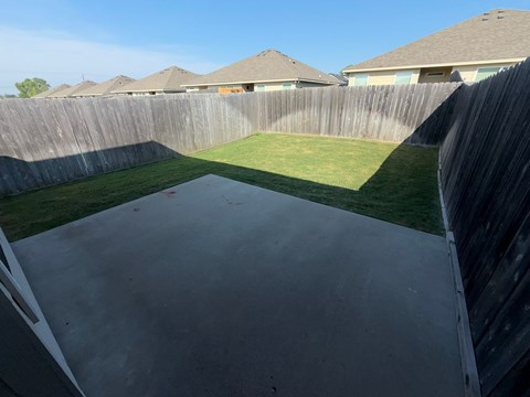 A concrete patio surrounded by a wooden fence.
