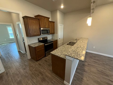 A kitchen with granite countertops and wooden cabinets.