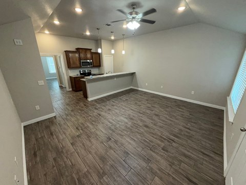 A spacious room with wood flooring and a ceiling fan.