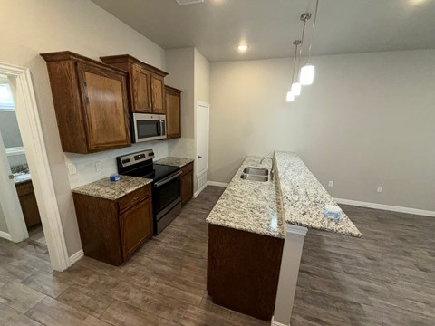 A kitchen with granite countertops and wooden cabinets.