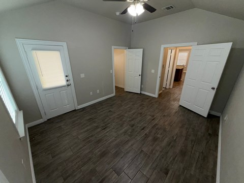 A room with a ceiling fan and wooden flooring.