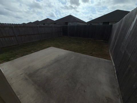 A concrete ramp leads to a backyard with a wooden fence.