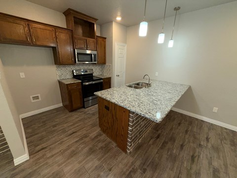A kitchen with a granite countertop and wooden cabinets.