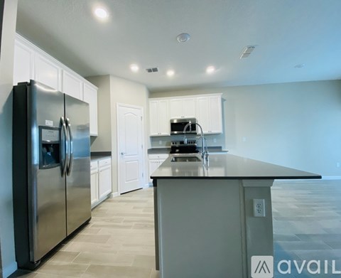 A kitchen with a black refrigerator and white cabinets.