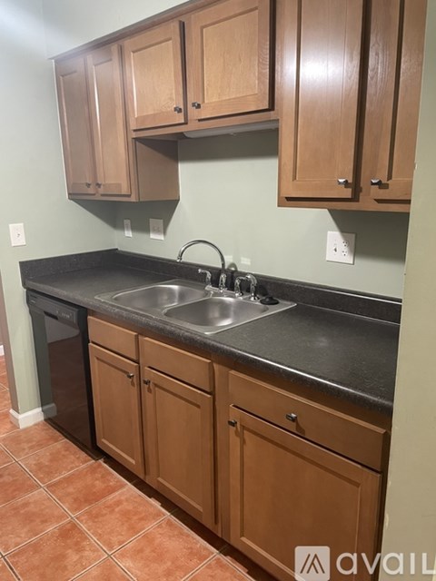 A kitchen with brown cabinets and a black countertop.