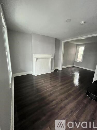 A room with wood flooring and a white fireplace.