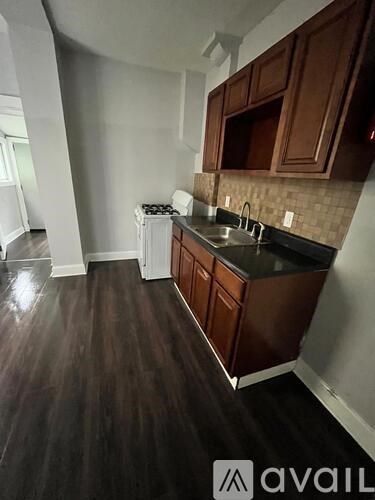 A kitchen with dark wood floors and brown cabinets.