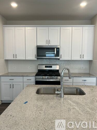 A kitchen with white cabinets and a granite countertop.