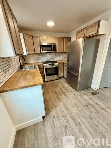 A kitchen with wooden cabinets and a stainless steel refrigerator.