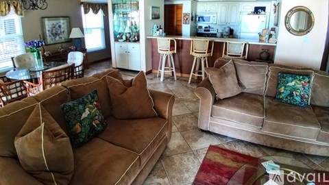 A living room with a brown couch and a glass table.