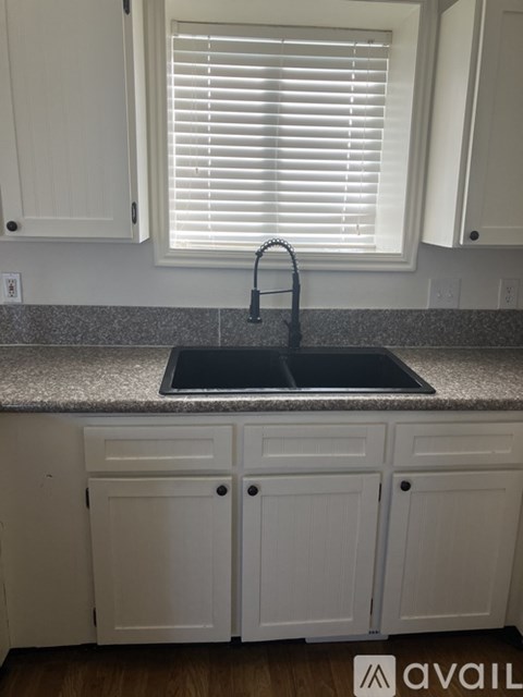 A kitchen with white cabinets and a granite countertop.