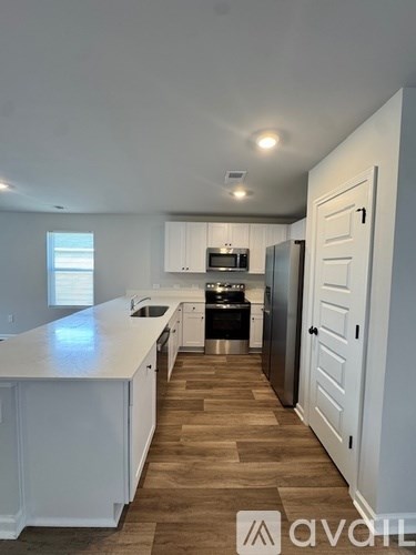 A kitchen with white cabinets and a wooden floor.