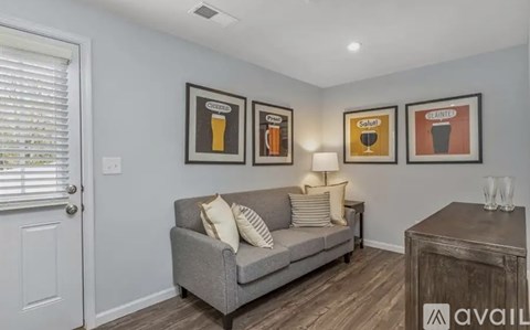 A living room with a grey couch and three framed pictures on the wall.