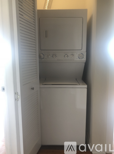 A small white washing machine is in a narrow space.
