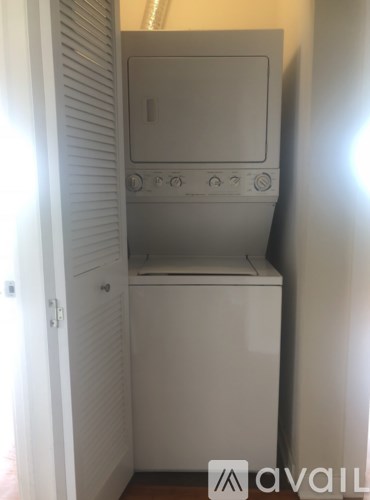 A small white washing machine is in a narrow space.