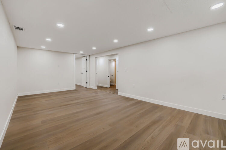 A spacious room with wooden flooring and white walls.