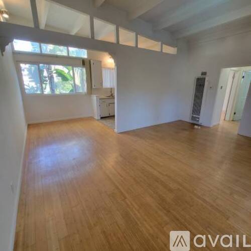 A spacious room with wooden flooring and white walls.