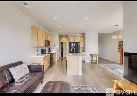A living room with a brown leather couch and wooden cabinets.