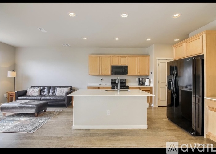 A kitchen with a black refrigerator and wooden cabinets.