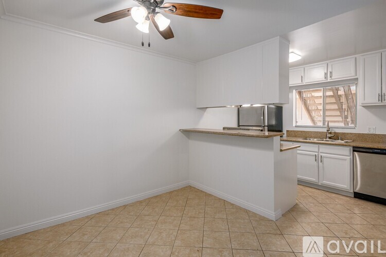 A kitchen with white cabinets and a fan on the ceiling.