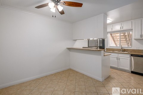 A kitchen with white cabinets and a fan on the ceiling.