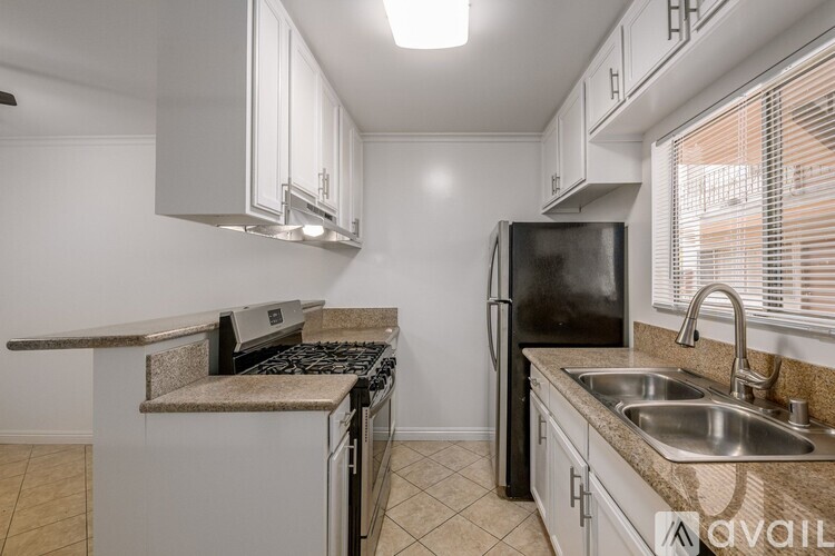 A kitchen with a black refrigerator, stove, and sink.