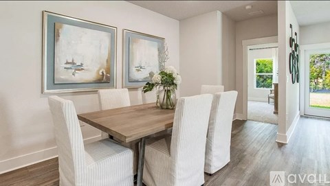A dining room with a wooden table and white chairs.