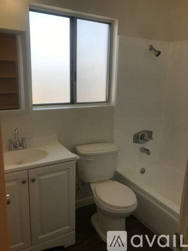 A white toilet sits in a bathroom next to a sink and a bathtub.