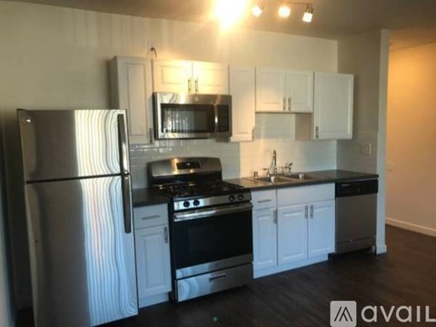A kitchen with white cabinets and a stainless steel refrigerator.
