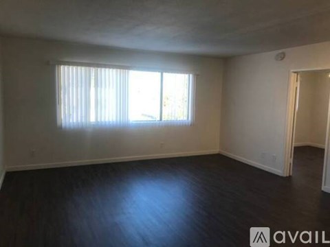 A spacious room with wooden floors and a large window.
