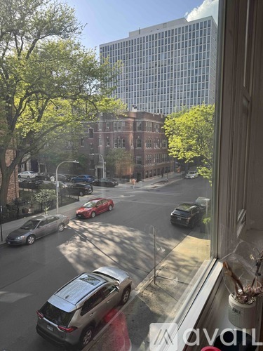 A view from a window looking out at a street with cars and buildings.