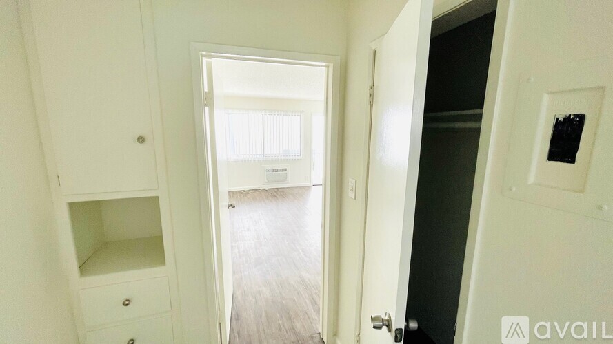 A white hallway with a door on the right and a cabinet with drawers on the left.