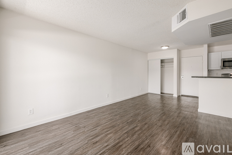 A spacious room with wooden flooring and white walls.