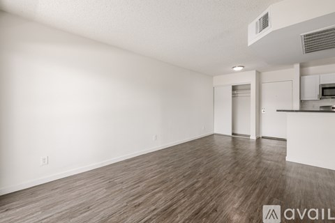 A spacious room with wooden flooring and white walls.