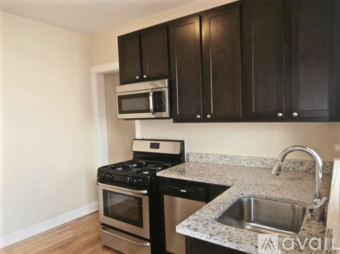 A kitchen with black cabinets and a granite countertop.