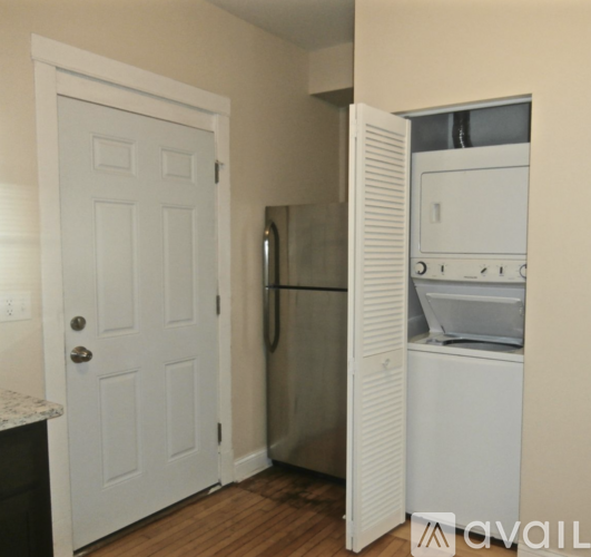 A white door is open to a kitchen with a refrigerator and dishwasher.