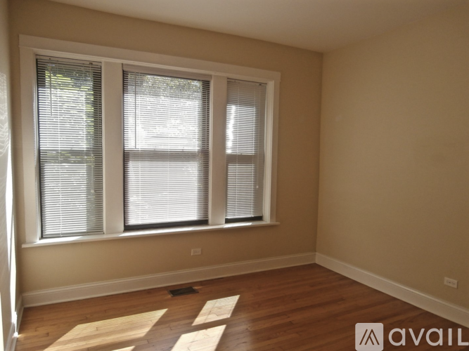 A room with wooden flooring and a window with blinds.