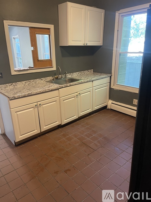 A kitchen with brown tiles and white cabinets.