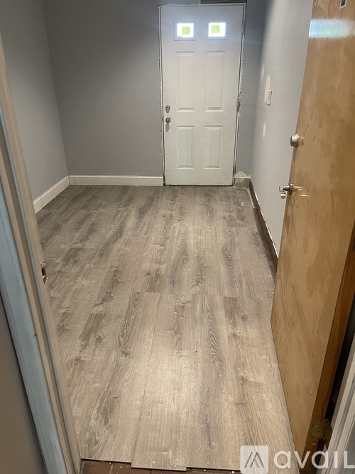A hallway with a white door and wooden flooring.