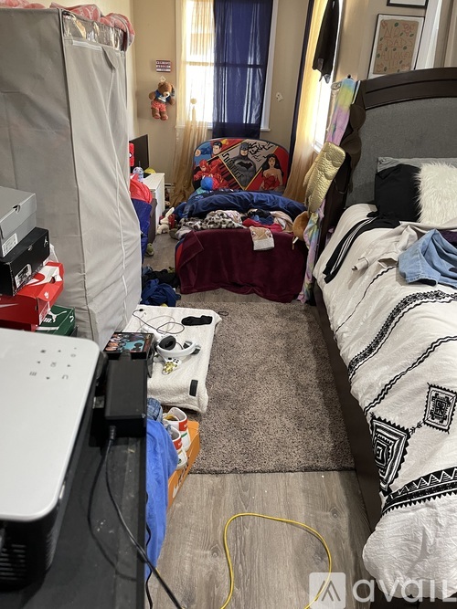 A messy bedroom with a bed, a desk, and a TV.