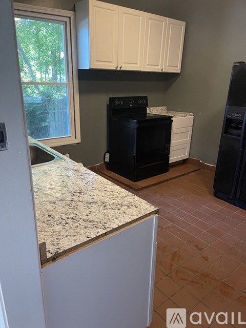 A kitchen with a black oven and white cabinets.