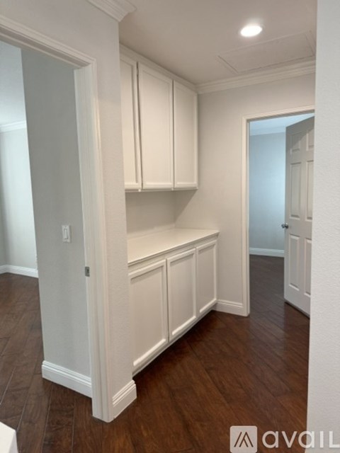 A kitchen with white cabinets and wooden floors.