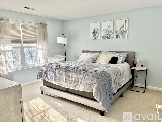 A bedroom with a large bed and a window with blinds.