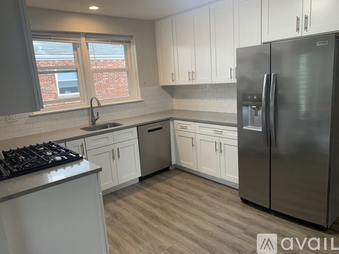 A kitchen with white cabinets and a stainless steel refrigerator.