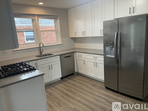 A kitchen with white cabinets and a stainless steel refrigerator.