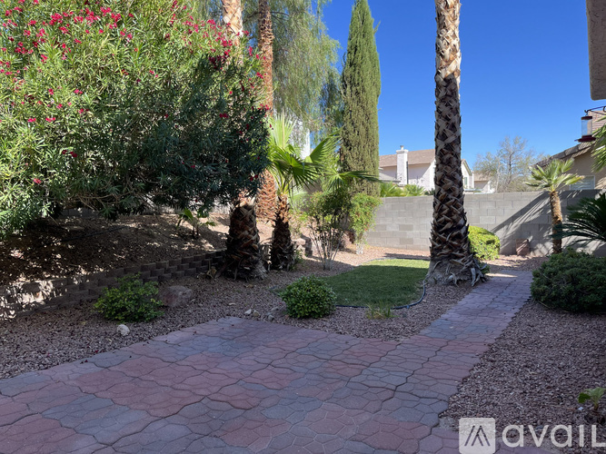 A garden with a red brick pathway and a variety of plants and trees.